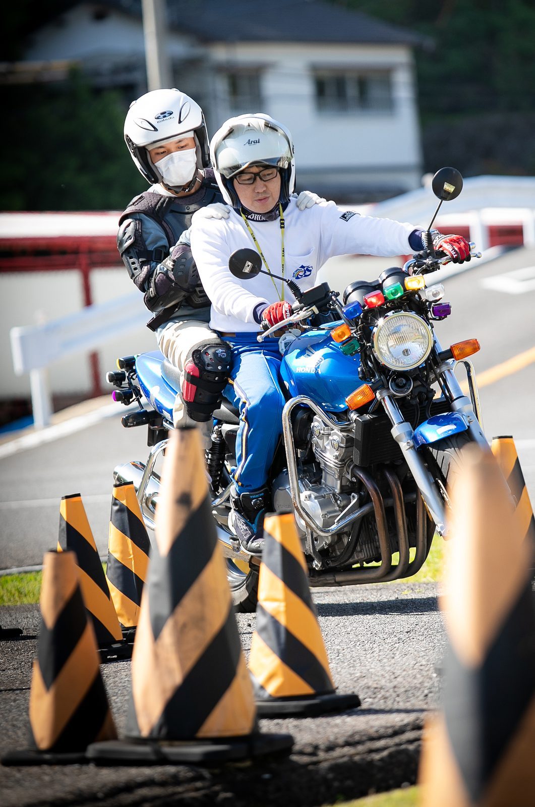 指導員が後ろで見守る中、教習生がバイクで走る
